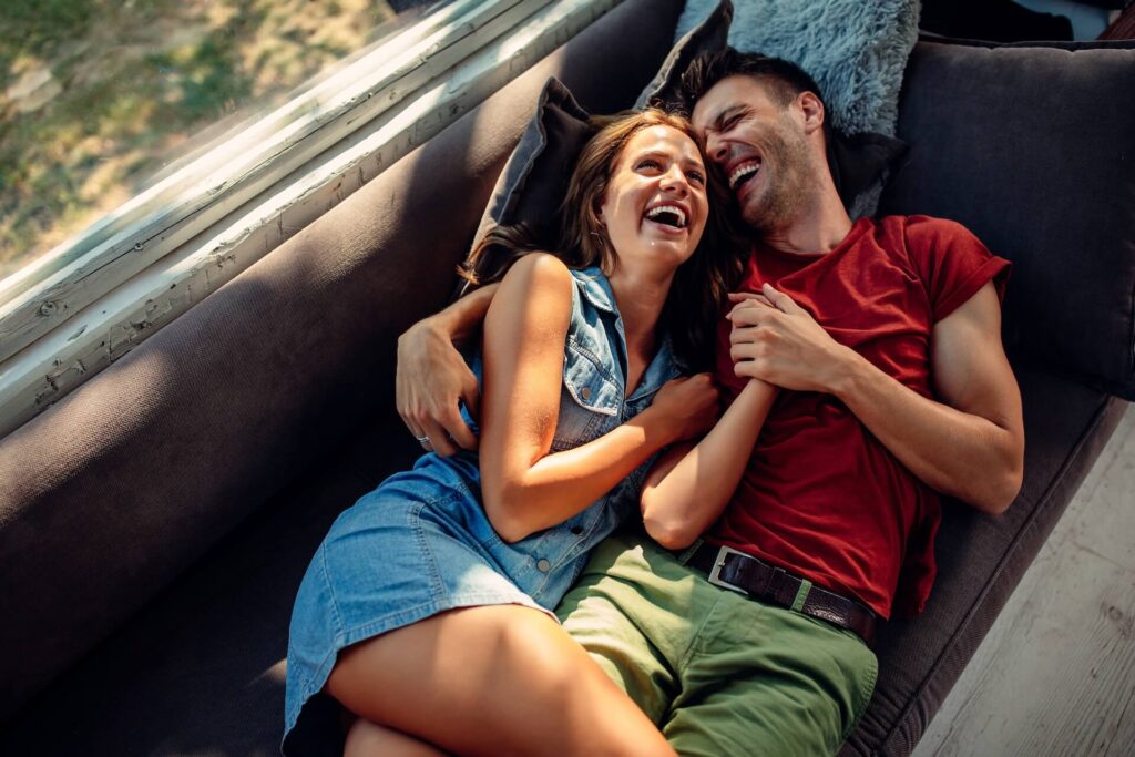 Happy couple lying on the sofa and laughing