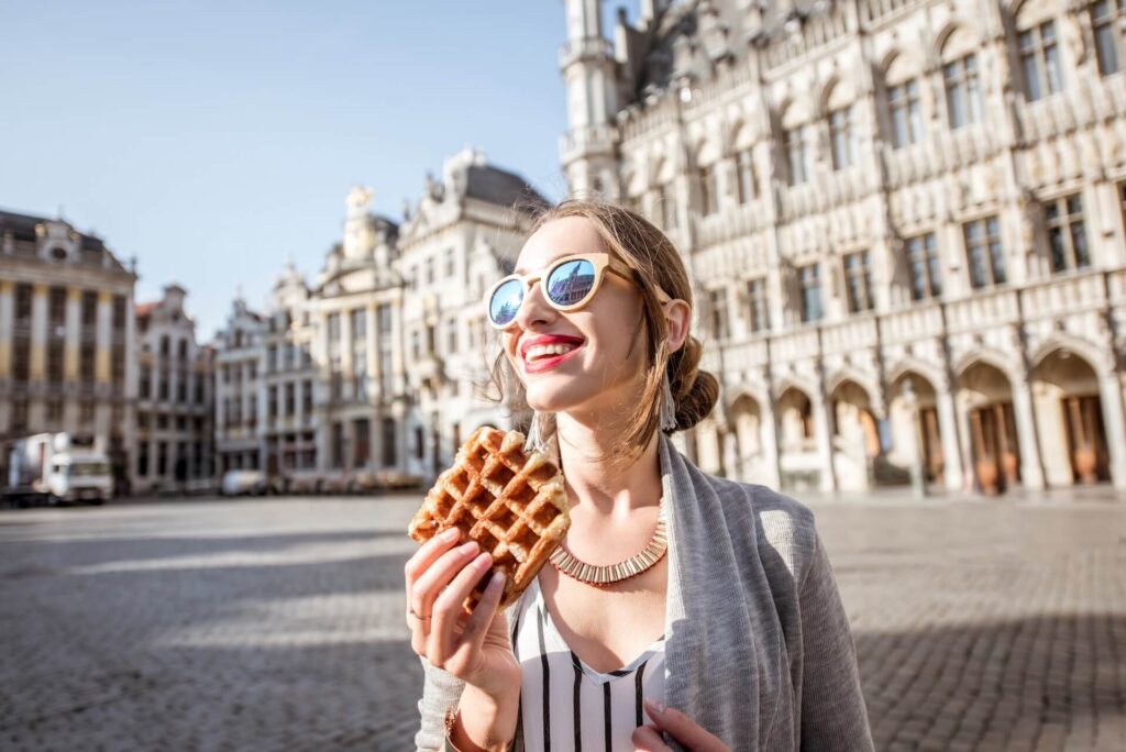 A girl with sunglasses smiling and holding some pastry
