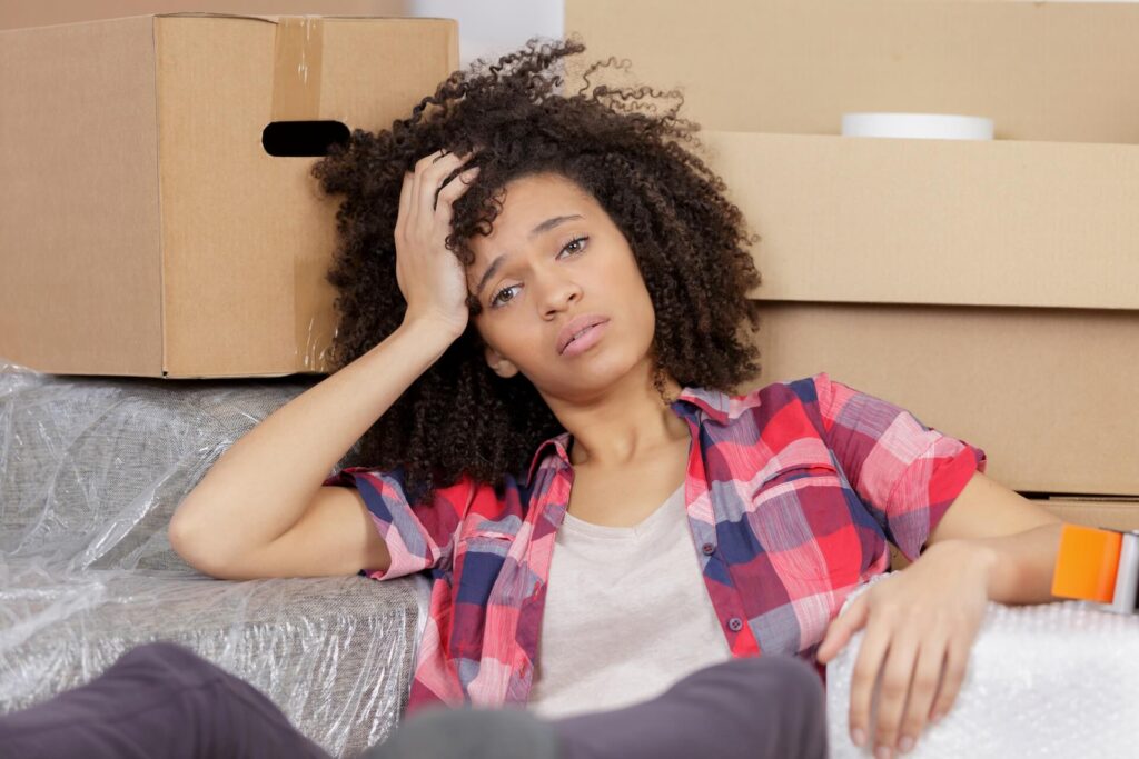 A girl worried about moving overseas surrounded by boxes