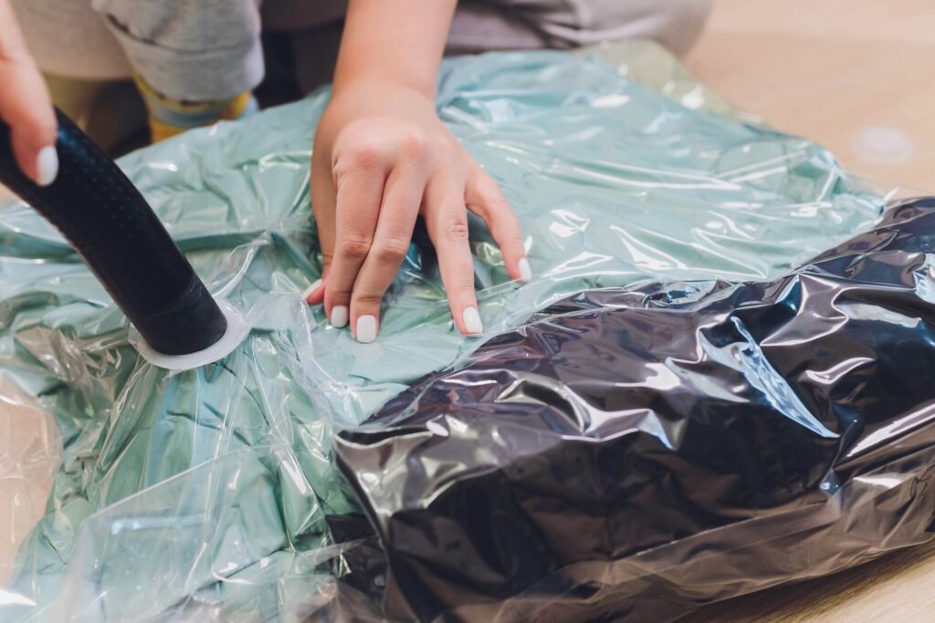A woman off-screen packing clothes in a vacuum-sealed bag for moving internationally