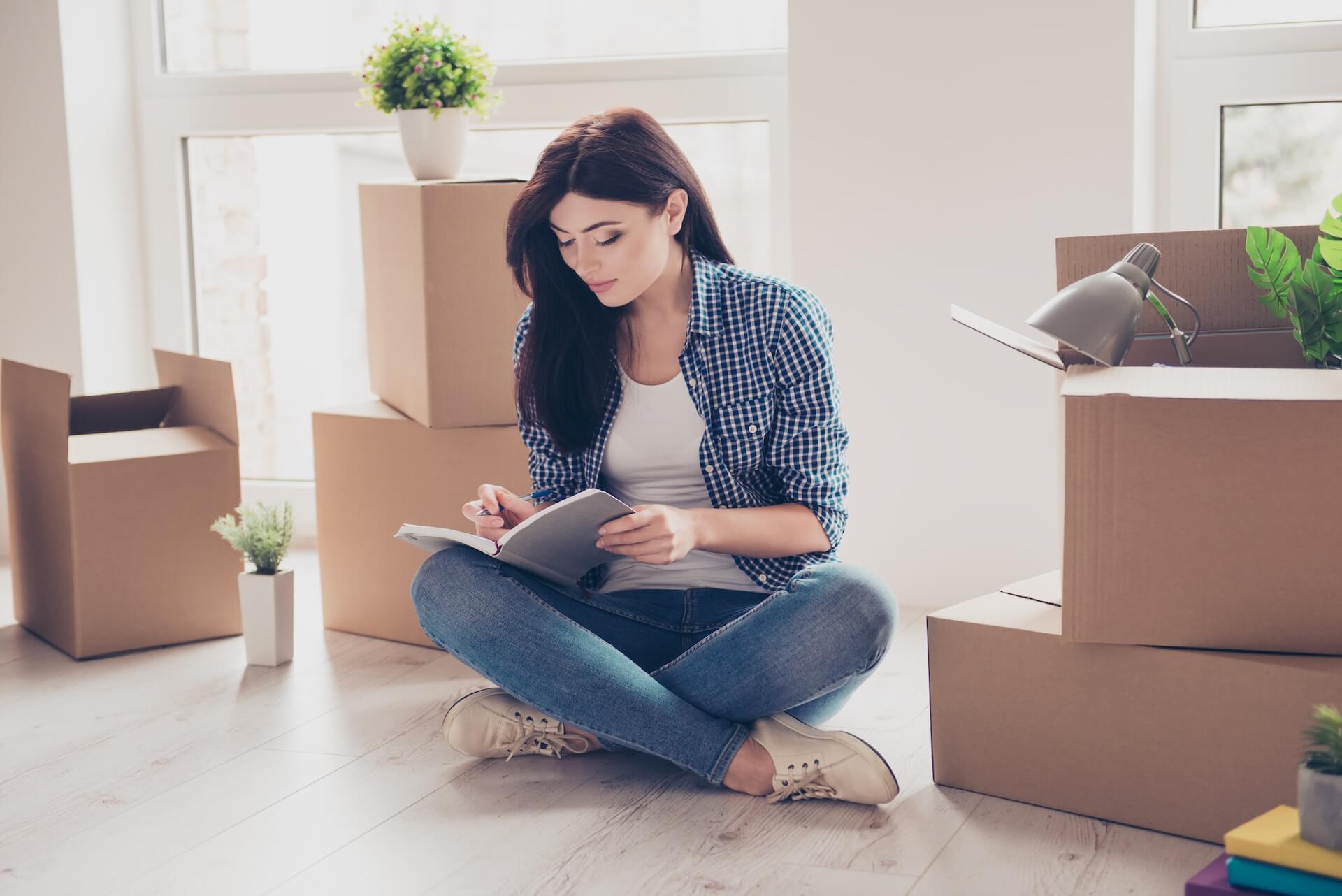 Girl planning writing in a notebook surrounded by boxes