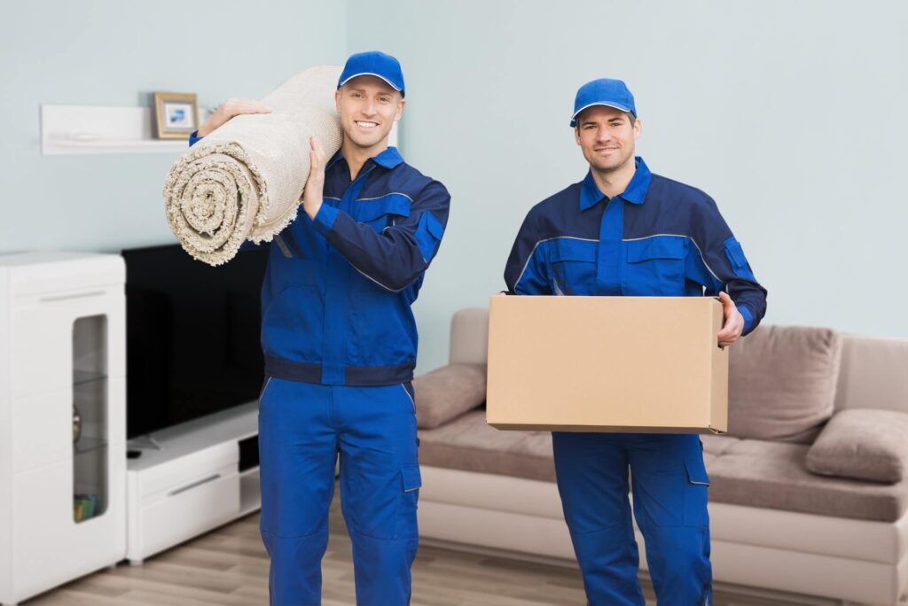 Two international movers holding a rolled-up carpet and a box