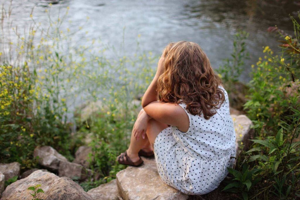 A woman sitting by the lake