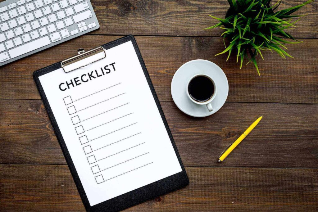 A checklist, keyboard, coffee, pen, and a plant on the table