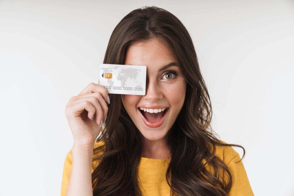 A happy woman holding a credit card over her face