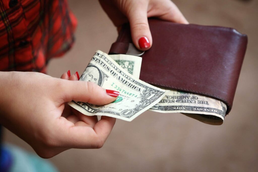 A woman holding a dollar and a wallet